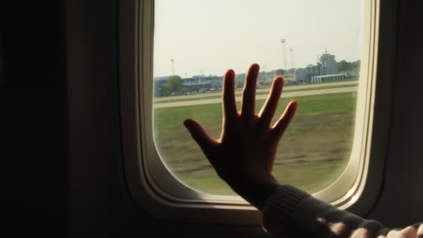 子供の飛行機の窓に触れる手、クローズ アップ。飛行機でウィンドウの背景に対してチャイルズ ヤシのシルエット。フライトの安全性の概念. — ストック動画