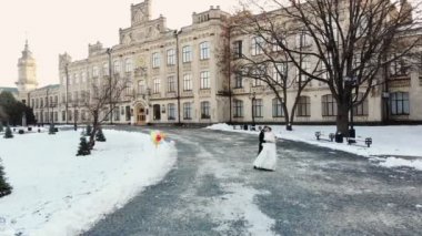 Düğün kış. Yeni evli çiftin gelinlik havadan görünümü bir karla kaplı Park, antik mimari ve kaldırım taşları arka planı düğün dans dans