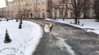 Düğün kış. Havadan görünümü, yeni evli iki gelinlik içinde antik mimari ve taş döşeme arka planı karla kaplı parkın içinden renkli balonlarla runing vardır.