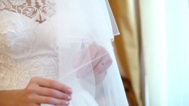 Gelin ücretleri. yakın çekim, arka planı beyaz dantel elbise bembeyaz bir peçe ile nazik bir manikür Gelinler elele tutuşun. Düğün elbise detayları, yakın çekim.