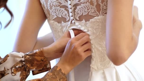Närbild, bruden avgifter. bruden är klädd för bröllopet. Brudtärna skosnören upp vit spets klänning med band. Bröllop klänning detaljer, närbild. — Stockvideo