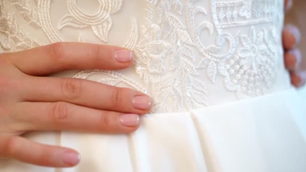 Плата за невесту. невеста одета для свадьбы. крупным планом руки невесты с нежным маникюром на фоне белого кружевного платья. Детали свадебного платья, крупным планом . — стоковое видео