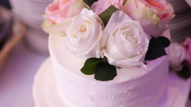 Close-up, bolo de três andares de creme de neve branco, decorado com rosas. bolo de casamento tradicional, tradições de casamento, acessórios . — Vídeo de Stock
