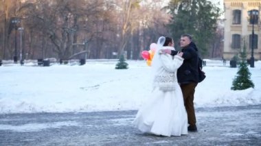 Düğün kış. Yeni evli çift düğün elbiseler düğün dansı bir karla kaplı Park, antik mimari ve kaldırım taşları arka planı dans ediyor