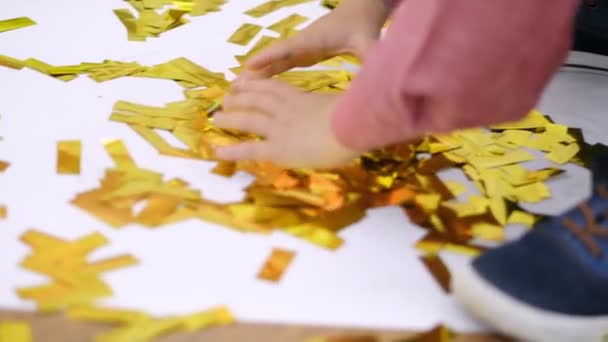 Close-up, childrens handen spelen met gouden glitters, gouden spangles van crackers, feestelijke klatergoud, decoraties. — Stockvideo