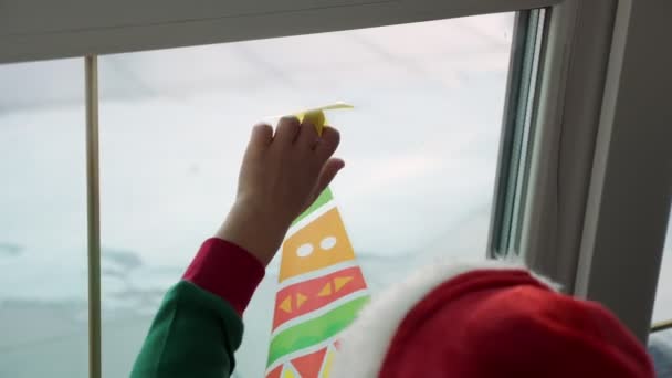 Primer plano, la gente decora la ventana de la casa con decoraciones de Navidad, pegatinas . — Vídeo de stock