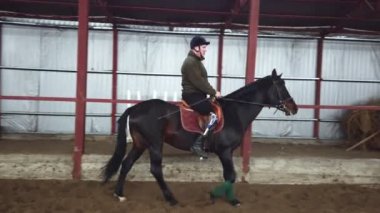 Özel hangarda bir Engelli genç bir siyah, safkan at, hippoterapi binmek öğrenir. adamın sağ ayağı yerine yapay bir kol var. Engelliler ile rehabilitasyonu kavramı