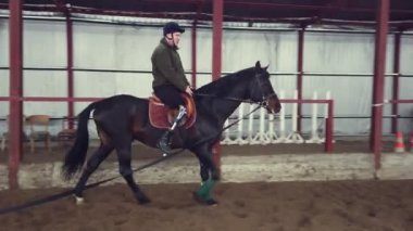 Özel hangarda bir Engelli genç bir siyah, safkan at, hippoterapi binmek öğrenir. adamın sağ ayağı yerine yapay bir kol var. Engelliler ile rehabilitasyonu kavramı