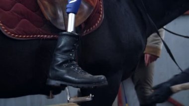 yakın çekim, erkek sürücü, bacak, protez, stirrups yapay bacak koymak için yardım olmadan devre dışı. adam ata, hippoterapi binmek öğrenir. hayvanlarla Engelli rehabilitasyonu kavramı.