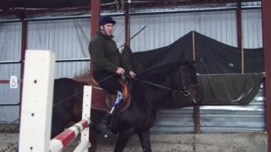 Özel hangarda bir Engelli genç bir siyah, safkan at, hippoterapi binmek öğrenir. adamın sağ ayağı yerine yapay bir kol var. Engelliler ile rehabilitasyonu kavramı