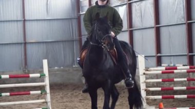 Özel hangarda bir Engelli genç bir siyah, safkan at, hippoterapi binmek öğrenir. adamın sağ ayağı yerine yapay bir kol var. Engelliler ile rehabilitasyonu kavramı