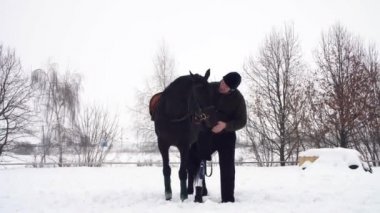 kış, Engelli adam karlı alan siyah ata yakın duruyor. adam bir namlu bir at vuruş. Sağ bacağı yerine protez yaşamalı. o ata, hippoterapi binmek öğrenir. rehabilitasyonu