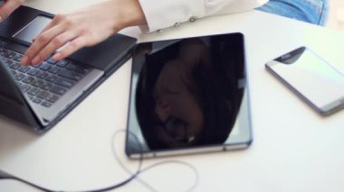 yakın çekim, bir dizüstü yanında beyaz bir masaüstü bir iş kadını gözlüklü yüz tablet ekran yansıtılır. bir şey üstünde a laptop klavye yazmakta olduğunu