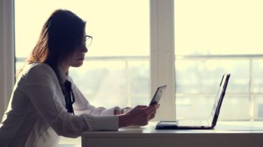 Genç bir kadın memur, memur sosyal ağlar göz atan bir cep telefonu, iş, bir ofiste onun kısa kahve molası sırasında dinlenmek. Ofis boşaltma psikolojik yükü kavramı iş.