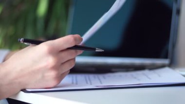 yakın çekim, tutan bir siyah kalem, bir belge, iş grafikleri Masaüstü, dizüstü bilgisayar, yanındaki erkek eller. iş kadını ofiste belgelerle çalışma.