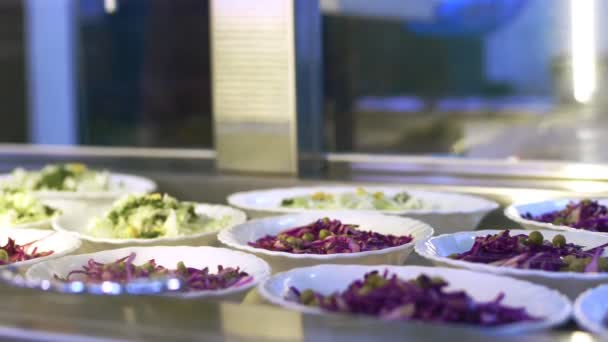 Nahaufnahme, Vitrine mit Salaten in der Kantine, Messehalle, Cafeteria, Restaurantbuffet. Buffet-Mitarbeiterin legt Essen auf Vitrine der Selbstbedienungskantine aus — Stockvideo