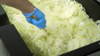 yakın çekim, eldiven aşçı taze, kıyılmış soğan çok büyük bir sanayi için kavurma tavada pişirme koyar. soğan kavurma zaman karışımları. Yemekhanede, Restaurant pişirme işlemi. soğan