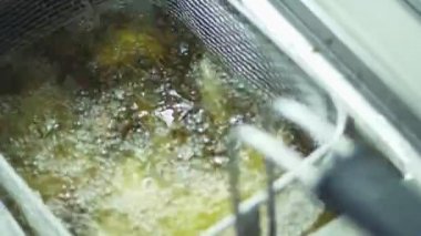 yakın çekim, eldiven aşçı patates kavurma için özel bir tablo tutar. aşçı adet patates, patates kızartması yağı kaynar pişiriyor. patates kızartması, yemekhane, Restaurant pişirme işlemi.