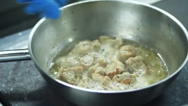 Γκρο πλαν, ο μάγειρας ετοιμάζει διαφορετικά τρόφιμα στη σόμπα. stews κρέας σε ένα skillet, παν. Επαγγελματικός αρχιμάγειρας ψητά κρεμμύδια και τα καρότα, που λειτουργεί σε μια σύγχρονη κουζίνα με διαφορετικά συστατικά — Αρχείο Βίντεο