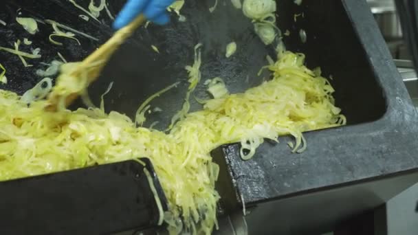 Primer plano, un cocinero en guantes establece, vierte una gran cantidad de cebolla frita de una sartén industrial grande para asar, cocinar. proceso de cocción en comedor, restaurante. tostado de cebolla, cebolla frita — Vídeo de stock