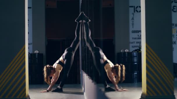 Strekken gymnast blonde mooie vrouw met aantrekkelijk lichaam, leggings, bindgaren zwarte top en sneakers, doen verticale split, met een voet op de wand en andere op de verdieping. Ze beweegt zeer opwindend — Stockvideo