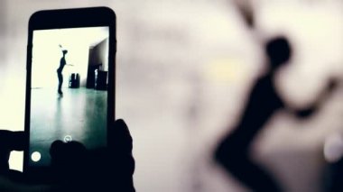 yakın çekim, smartphone monitör, karanlık bir şekil, bir kadının anahat çekim spor salonunda egzersiz gerçekleştirir. Kaslı kadın çapraz uygun egzersiz yapıyor. Fitness sınıfı kardiyo egzersiz