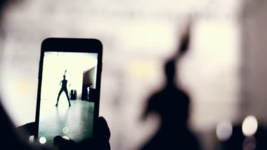 yakın çekim, smartphone monitör, karanlık bir şekil, bir kadının anahat çekim spor salonunda egzersiz gerçekleştirir. Kaslı kadın çapraz uygun egzersiz yapıyor. Fitness sınıfı kardiyo egzersiz