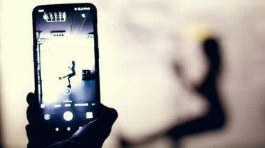 yakın çekim, smartphone monitör, karanlık bir şekil, bir kadının anahat çekim Trx döngüler, kayışlar, spor salonunda egzersiz gerçekleştirir. Kaslı kadın çapraz uygun egzersiz yapıyor. Fitness sınıfı kardiyo egzersiz