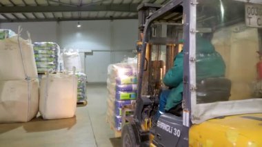 Ukrayna, Cherkasy, 25 Mart 2019: tarım şirketi Mais. Forklift sürücü istifleyici yükleyici ile mısır büyük paket paletleri istifleme, paletalır, büyük bir depodan taşır.