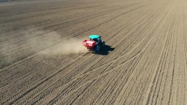 大轮子上的农用拖拉机的鸟瞰图穿过肥沃的农田，用种子钻铺开矿物肥料，在犁地上扬起巨大的灰尘。春季土壤栽培 — 图库视频影像