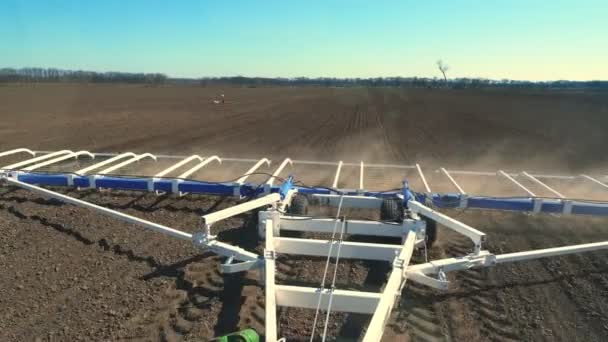 Vista da cabine do cultivador para o campo fértil da fazenda. trator arados, grades do solo com um grande arado de metal, levanta muita poeira em terras aráveis prepara o solo para semear — Vídeo de Stock