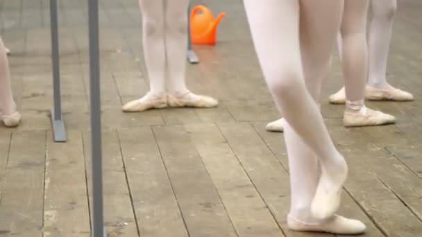 Close-up, jonge ballerina benen in ballet schoenen, pointes, in beige maillots, oefeningen uitvoeren in de buurt van Barre, op een oude houten vloer in een ballet school, tijdens ballet les — Stockvideo