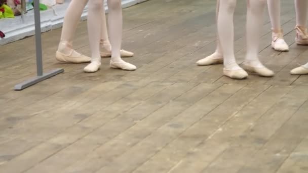 Крупный план, юные ноги балерины в балетных туфлях, пуантах, в бежевых трико, выполнять упражнения рядом с баром, на старом деревянном полу в балетной школе, во время урока балета — стоковое видео