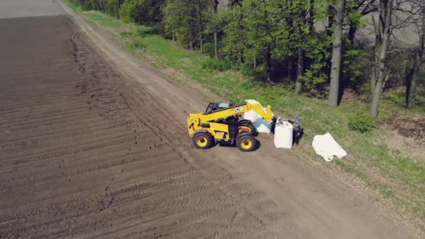 Ukrayna, Cherkasy, Mayıs 5, 2019: hava araştırma, yükleyici sahaya ekim mekanize makine patates için traktör patates büyük çuval getiriyor. patates traktör arkasına dökülür — Stok video