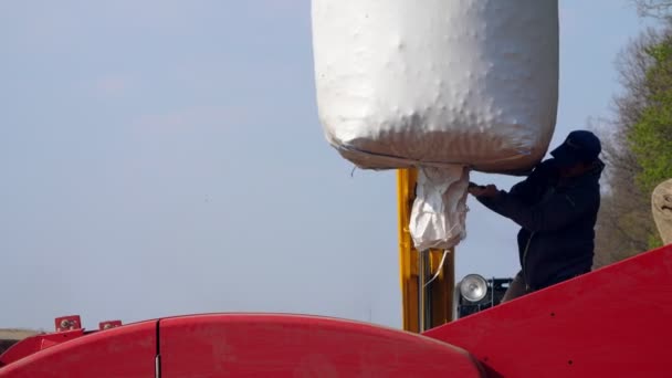 UCRANIA, CHERKASY, 5 DE MAYO DE 2019: las semillas de patata, las patatas se vierten en la parte posterior del tractor de una gran bolsa blanca. El siguiente es un trabajador. proceso de máquina mecanizada de plantación de patata en el campo — Vídeos de Stock