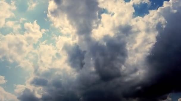 Timelapse, koyu mavi gökyüzü, gri gök gürültüsü bulutlar, yağmur bulutları çalışan. Güneşin nadir ışınları bulutların arasından yol yapar — Stok video