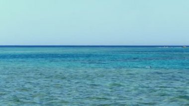 yaz, deniz manzarası. su yüzeyi, sessiz sakin turkuaz deniz ve mavi gökyüzü. tatilciler denizde şnorkelle yüzmek için maskelerle yüzerler. plajdan denize manzara.