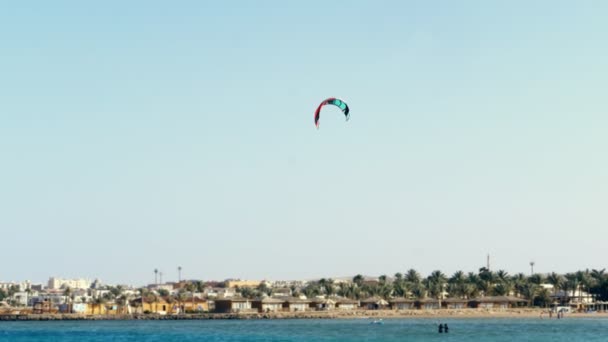 Paracadute da kitesurf aleggia sopra il bordo delle acque contro il cielo blu chiaro. in estate, sulla spiaggia . — Video Stock