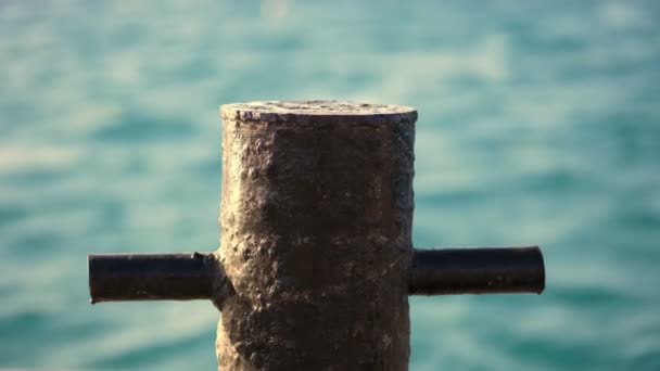 特写，旧金属生锈的系泊护栏是码头上的一根小杆，船被固定住，是一艘装有绳索和电缆的游艇。在海洋的背景。深度聚焦 — 图库视频影像