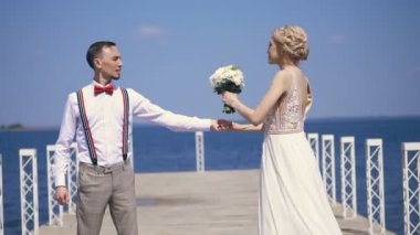 güzel yeni evli çift, gelin ve damat açık havada dans, güzel bir iskelede, mavi deniz ve gökyüzüne karşı. yaz güneşli gün. Düğün
