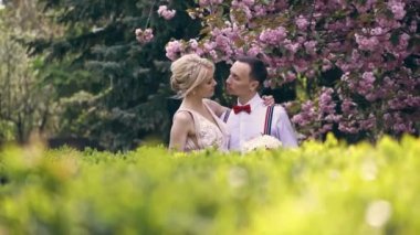 Genç, güzel bir çift, yeni evliler sarılır, birbirlerine bakar, çiçek açan sakura 'nın altında dururlar. Bahar güneşli bir gün. düğün