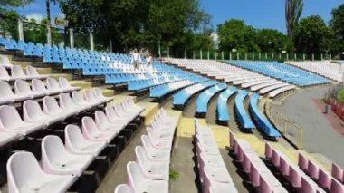 havadan video, stadyumda, düğün kıyafetleri yeni evliler beyaz ve mavi koltuklar arasında yürüyor . bahar güneşli bir gün. Düğün