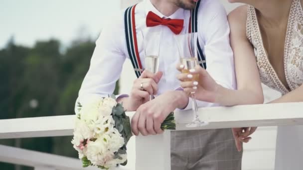 Крупный план, молодожены держат бокалы шампанского и свадебный букет — стоковое видео
