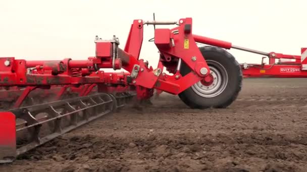 Gros plan, tracteur cultivateur cultive, creuse le sol. tracteur laboure le champ. tiller automatisé pour creuser le sol dans la ferme dans les terres fraîchement labourées. printemps — Video