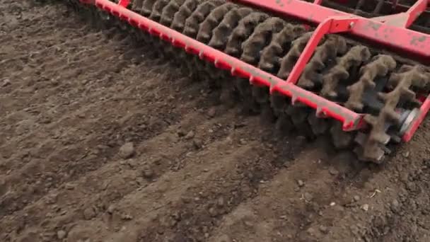 Gros plan, tracteur cultivateur cultive, creuse le sol. tracteur laboure le champ. tiller automatisé pour creuser le sol dans la ferme dans les terres fraîchement labourées. printemps — Video