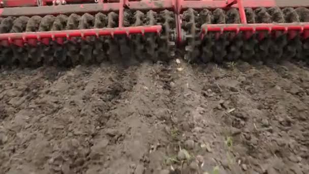 Gros plan, tracteur cultivateur cultive, creuse le sol. tracteur laboure le champ. tiller automatisé pour creuser le sol dans la ferme dans les terres fraîchement labourées. printemps — Video