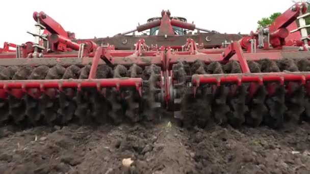 Close-up, tractor cultivator cultivates, graveert de bodem. tractor ploegen het veld. geautomatiseerde Tiller voor het graven van grond in de boerderij in vers geploegd land. Voorjaar — Stockvideo
