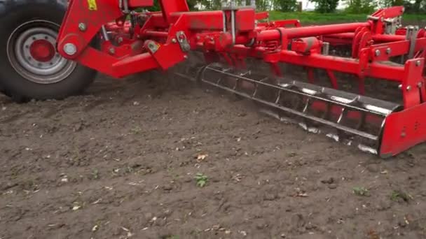 Primer plano, cultivador de tractores cultiva, cava el suelo. tractor arada el campo. timón automatizado para cavar tierra en la granja en tierras recién aradas. primavera — Vídeo de stock