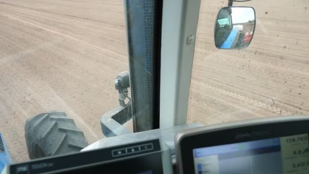 Primer plano, desde la cabina del conductor del tractor se puede ver el suelo recién arado del campo y la gran rueda del tractor . — Vídeo de stock