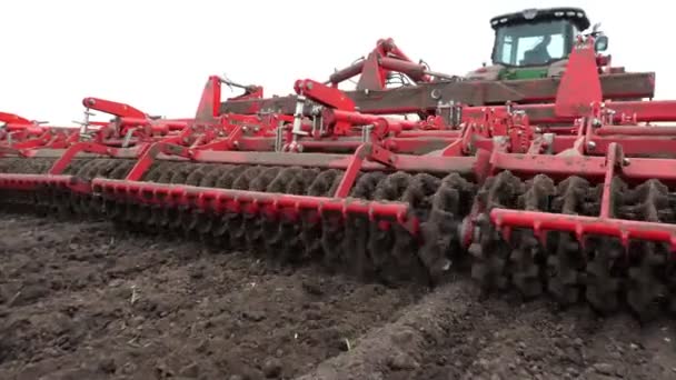 Крупным планом культиватор трактора культивирует, копает почву. Трактор вспахивает поле. автоматизированный культиватор для выкапывания почвы на ферме в свежевспаханную землю. весна — стоковое видео